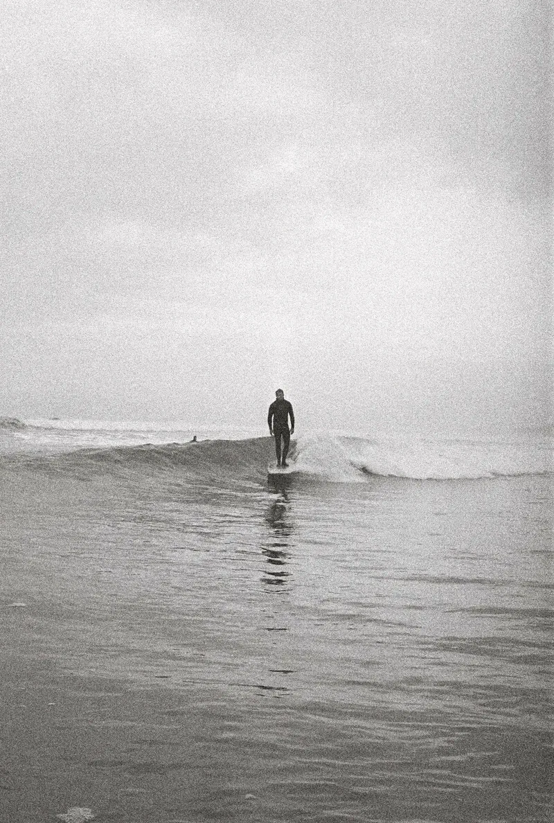 Black and white, a longboarder on a small wave in the fog