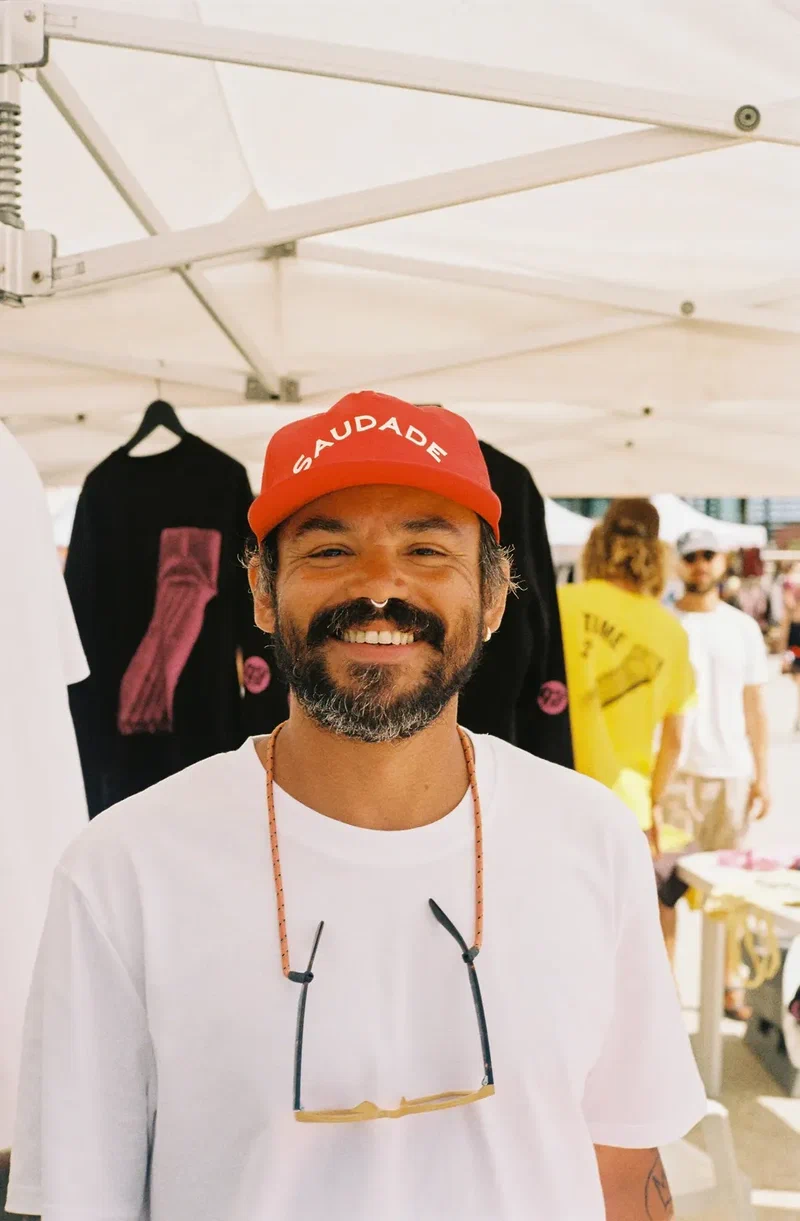 Smiling man in a red cap in front of a market stall
