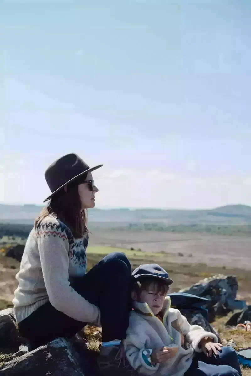 Une mère et son fils assis sur un rocher, face à la lande