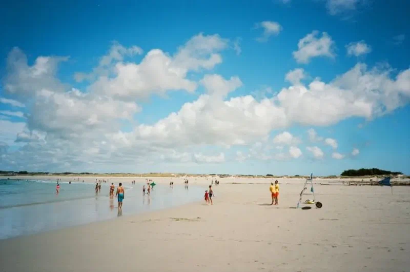 Grande plage de sable et baigneurs sous des nuages de beau temps