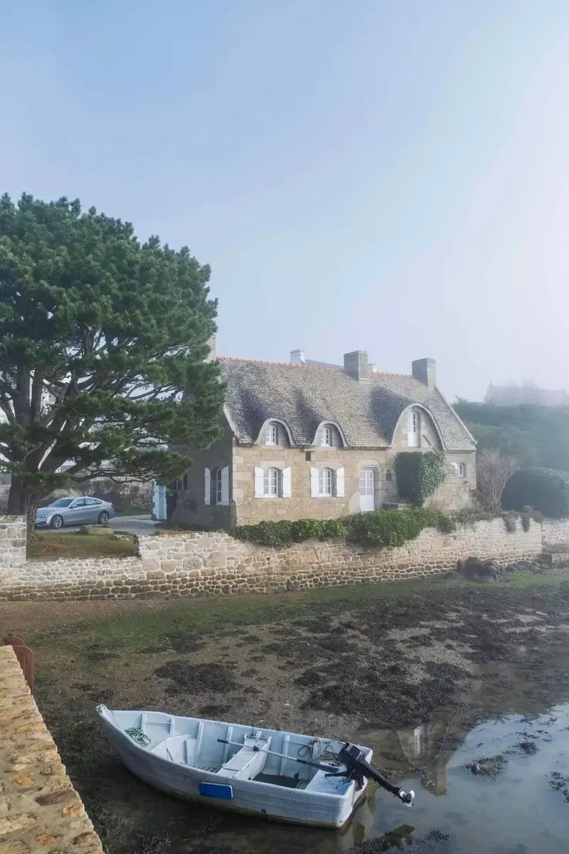 Chaumière et barque échouée au bord d'une ria bretonne