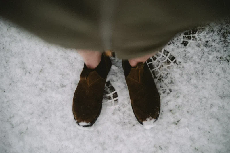 Brown boots on a frozen, hail-covered path