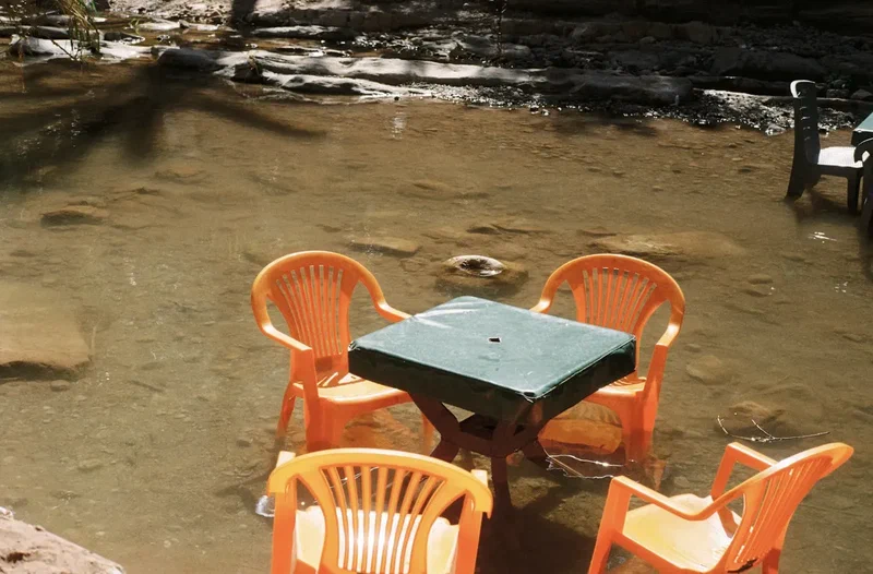 Orange plastic chairs around a table in a flooded garden
