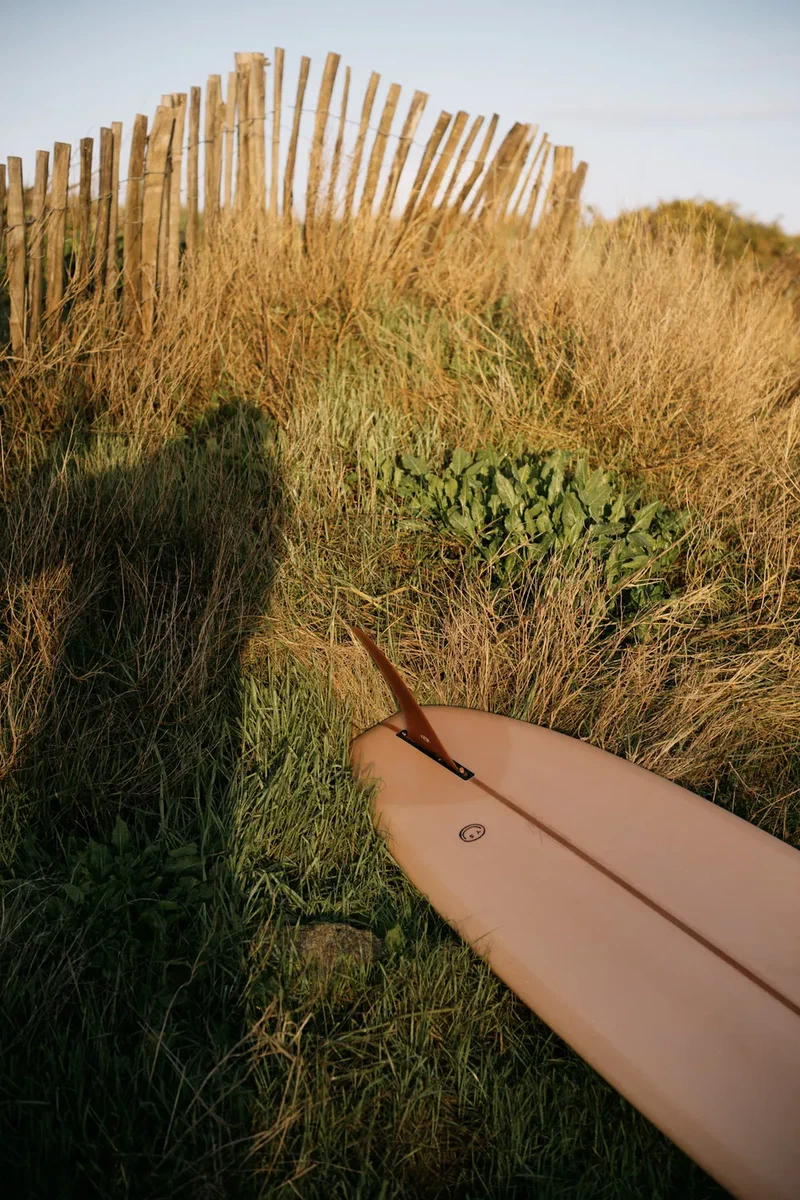 Shadow of the photographer and a surfboard in the dune grass