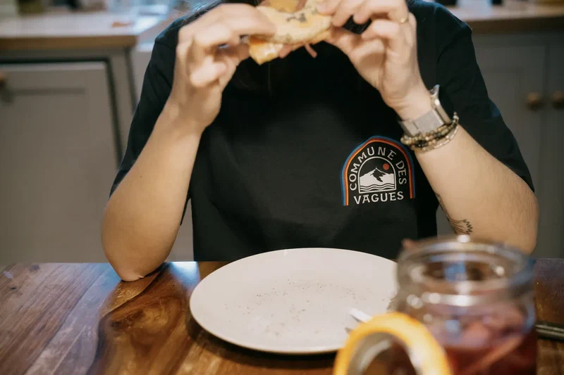 Person in a Vagues t-shirt eating at the kitchen table