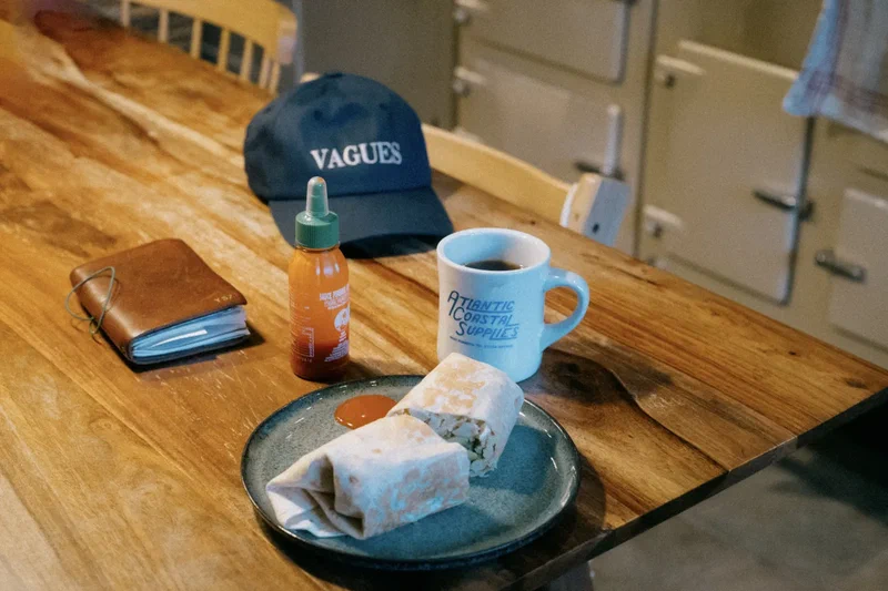 Breakfast table with a Vagues cap, coffee and a burrito
