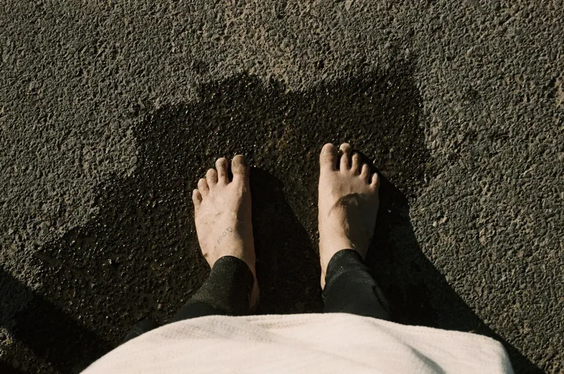 Bare feet in a wetsuit on wet asphalt
