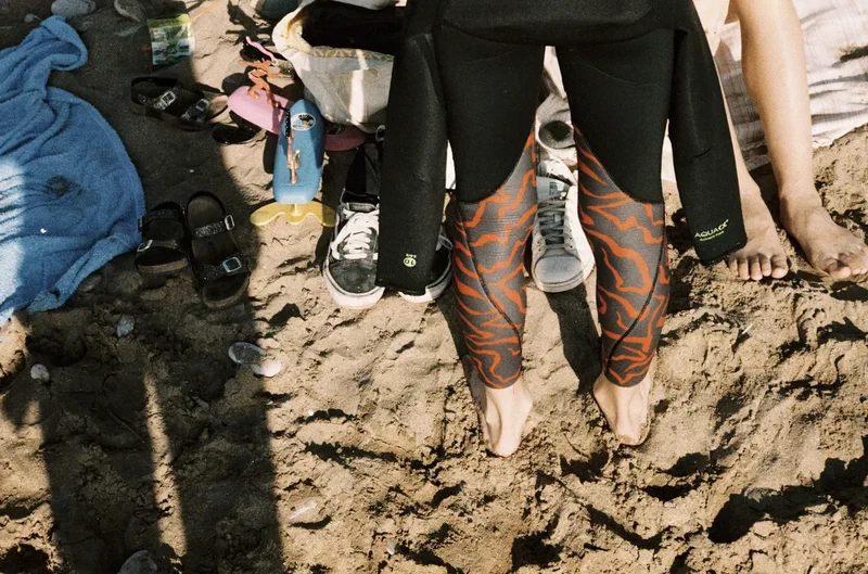 Surfers changing on the sand among towels and shoes