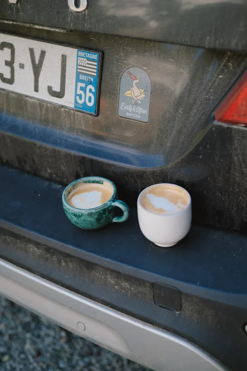 Two coffees on the bumper of a car with a Breton number plate