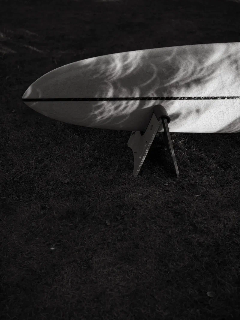 Surfboard on a stand in sharp shadows, black and white