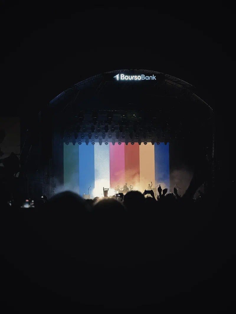 Concert stage lit in rainbow colours in a dark arena