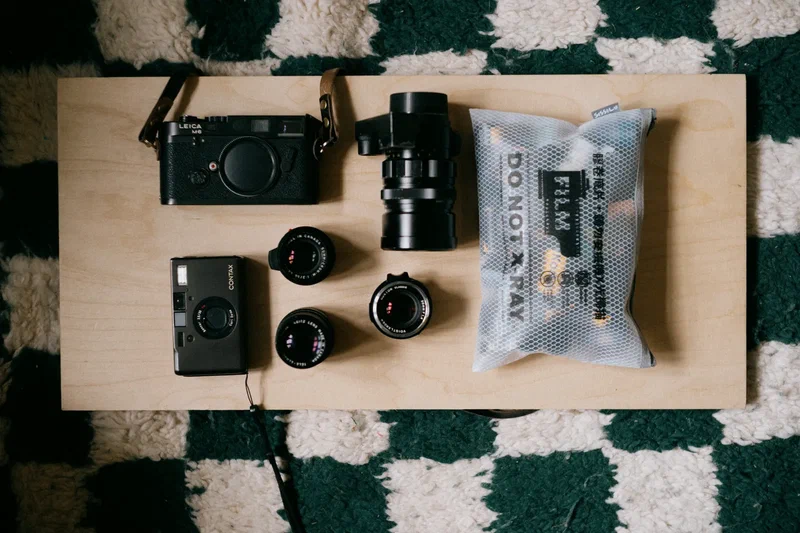 Leica cameras, lenses and a bag of film on a wooden board
