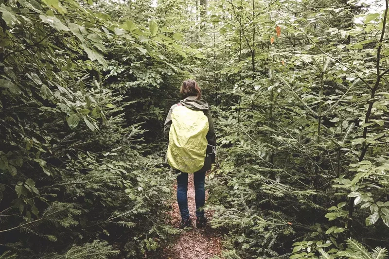 Randonneuse avec un sac jaune dans un sentier très vert