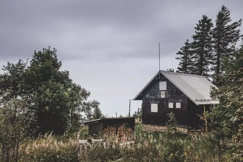 Chalet en bois sombre sous un ciel d’orage