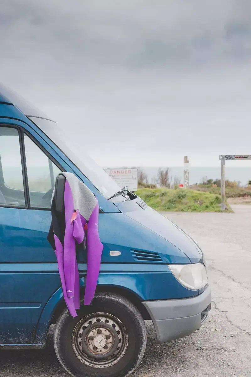 Combinaison violette qui sèche sur le rétroviseur d'un van bleu