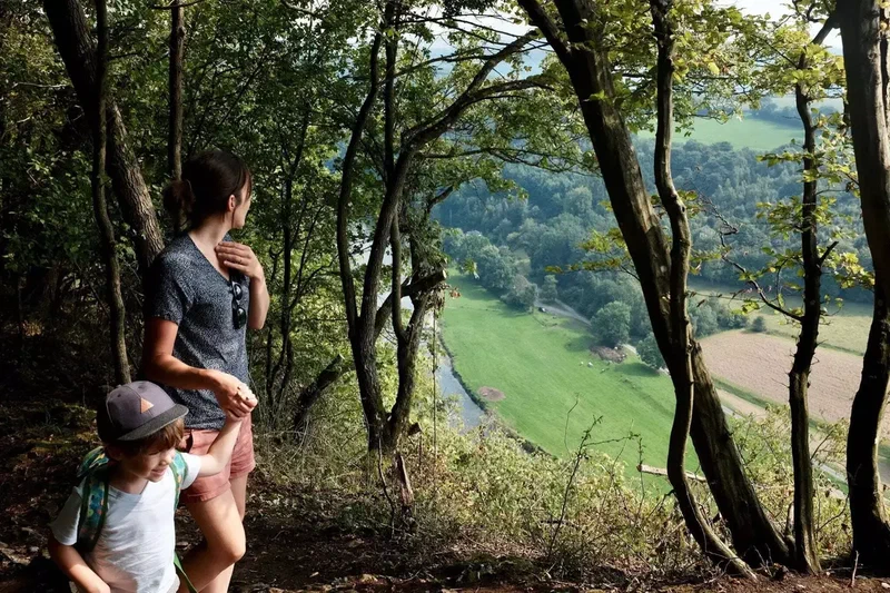 Une mère et son fils au bord du sentier, la vallée de l'Ourthe en contrebas