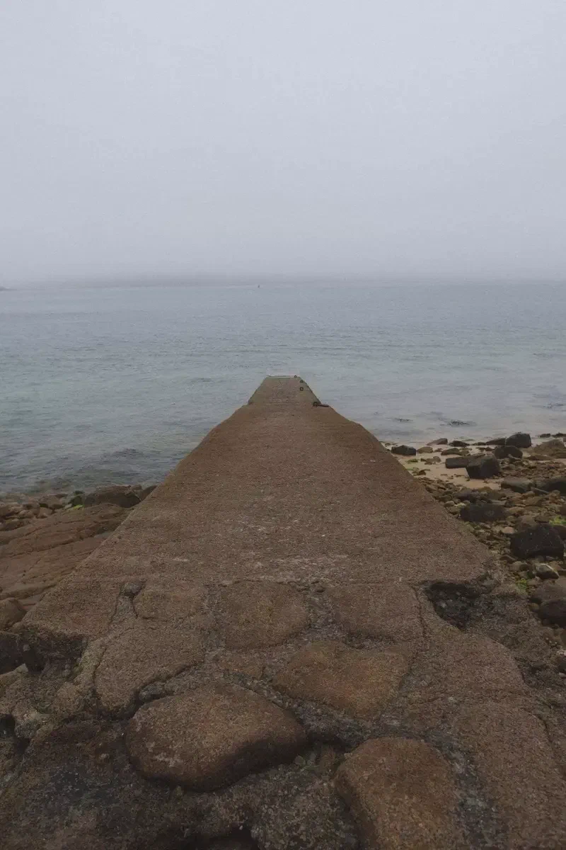 Cale de pierre qui s'avance dans la mer brumeuse