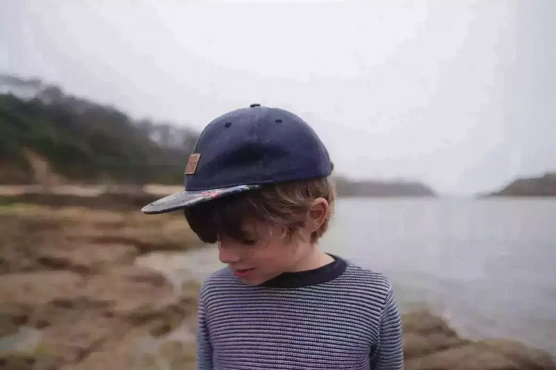 Enfant en casquette au bord de la mer à Berrien