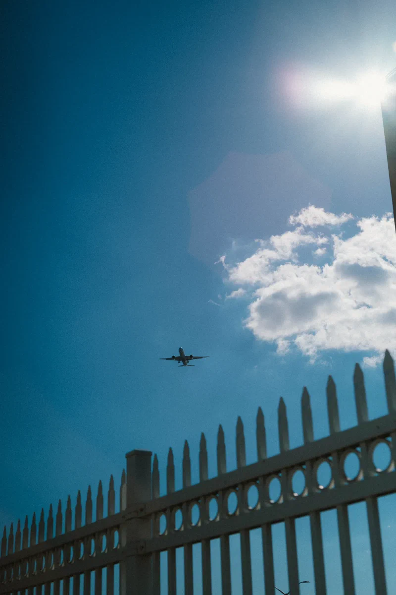 Avion qui passe dans un ciel bleu au-dessus d'une grille