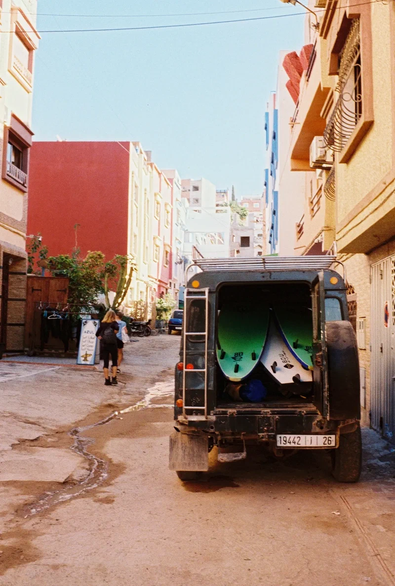 Land Rover chargé de planches dans une ruelle colorée