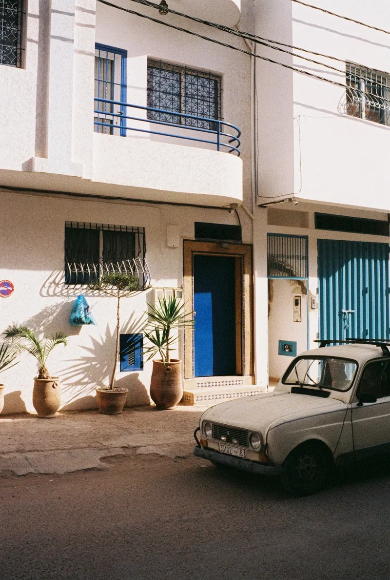Renault 4 garée devant une maison blanche aux portes bleues