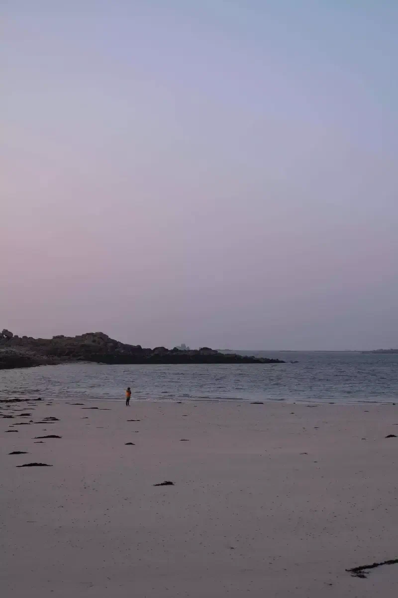 Promeneur sur une grande plage au coucher du soleil