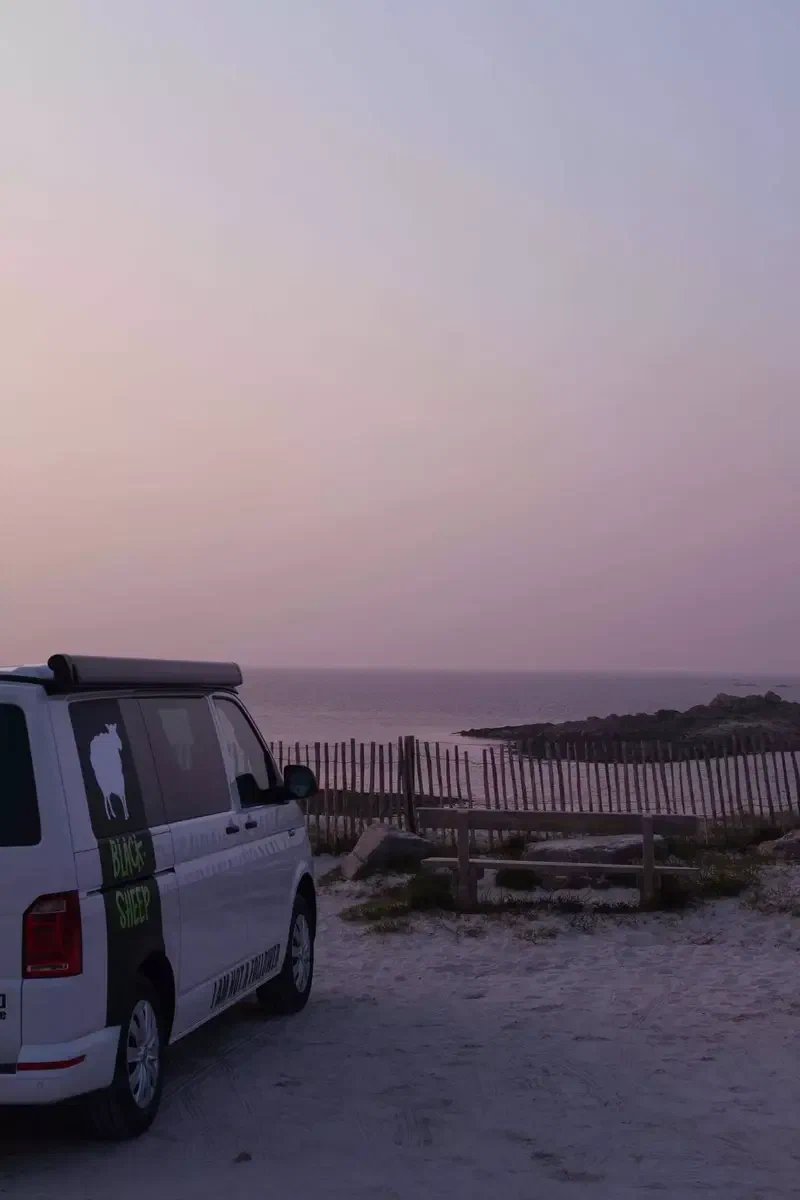 Van aménagé garé au bord d'une plage au crépuscule