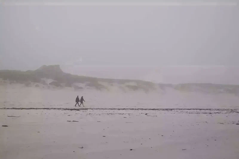 Deux promeneurs sur la plage dans la brume