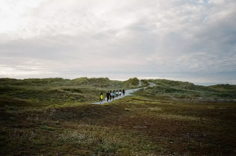 Surfeurs qui rejoignent la plage par le sentier dans les dunes