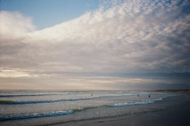 Vagues et surfeurs sous un ciel pommelé
